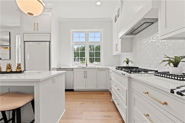 kitchen with white cabinetry, sink, stainless steel appliances, light hardwood / wood-style floors, and a breakfast bar