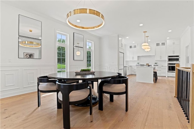 dining space with crown molding and light hardwood / wood-style flooring