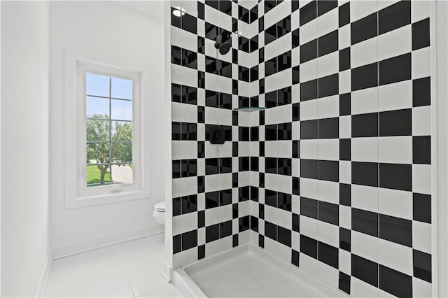 bathroom with toilet, tile patterned flooring, and tiled shower