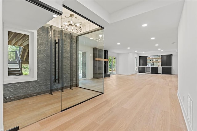 unfurnished living room with a large fireplace, wood-type flooring, and a notable chandelier