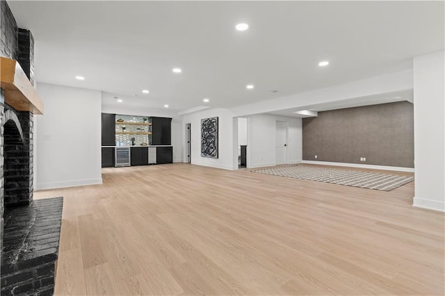 unfurnished living room featuring a brick fireplace, light hardwood / wood-style flooring, and beverage cooler