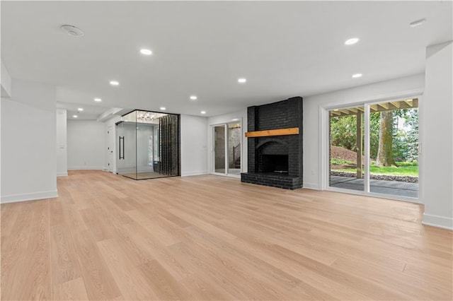 unfurnished living room with light wood-type flooring and a brick fireplace