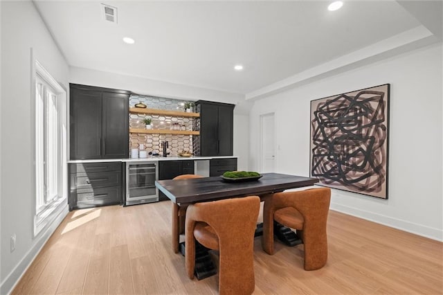 dining space featuring light hardwood / wood-style floors, beverage cooler, and indoor bar