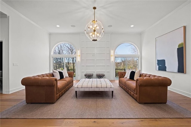 living room featuring hardwood / wood-style floors, crown molding, and an inviting chandelier