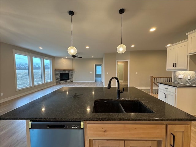 kitchen with white cabinetry, an island with sink, sink, dark stone countertops, and stainless steel dishwasher