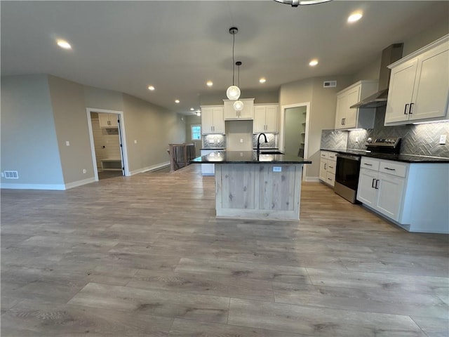 kitchen with stainless steel range with electric stovetop, white cabinetry, pendant lighting, and a center island with sink