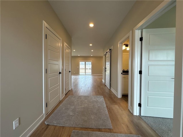 hallway featuring a barn door and light hardwood / wood-style flooring