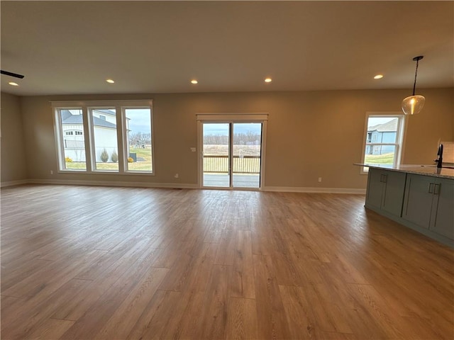 unfurnished living room featuring sink and light hardwood / wood-style flooring