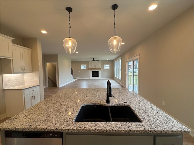 kitchen with hanging light fixtures, white cabinetry, sink, and light stone counters