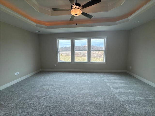 carpeted empty room with ceiling fan and a tray ceiling