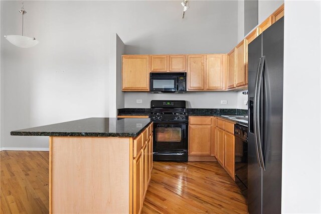 kitchen with light hardwood / wood-style flooring, black appliances, pendant lighting, a kitchen island, and light brown cabinetry