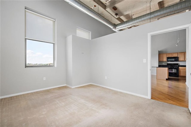 carpeted spare room with a towering ceiling