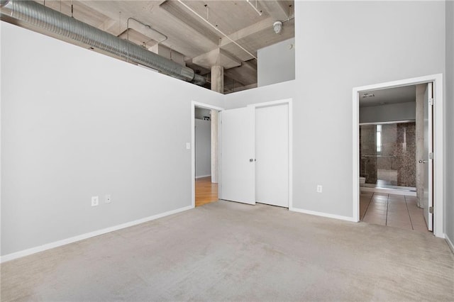 unfurnished bedroom featuring a towering ceiling and connected bathroom