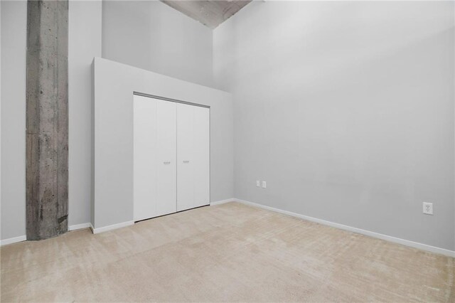 unfurnished bedroom featuring a closet, light colored carpet, and a high ceiling