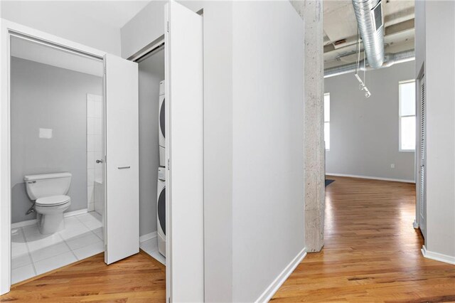 hallway featuring stacked washer and clothes dryer and light wood-type flooring