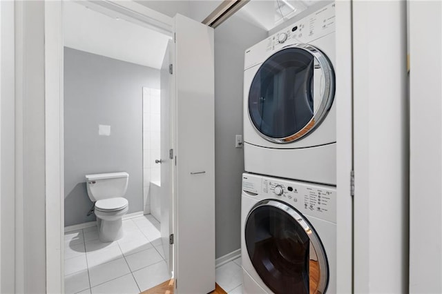 clothes washing area featuring stacked washer and dryer and light tile patterned floors