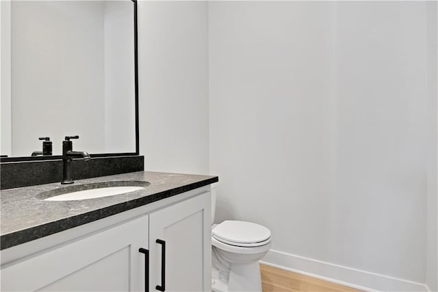 bathroom featuring wood-type flooring, vanity, and toilet