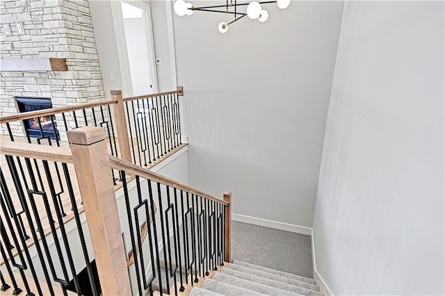 stairs featuring a fireplace, carpet floors, and a notable chandelier