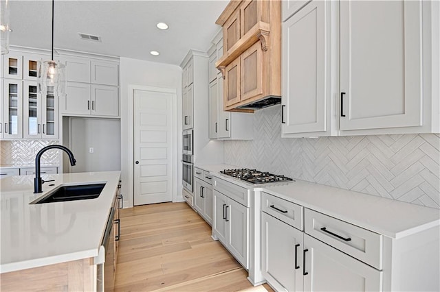 kitchen with decorative light fixtures, white cabinetry, sink, and stainless steel appliances