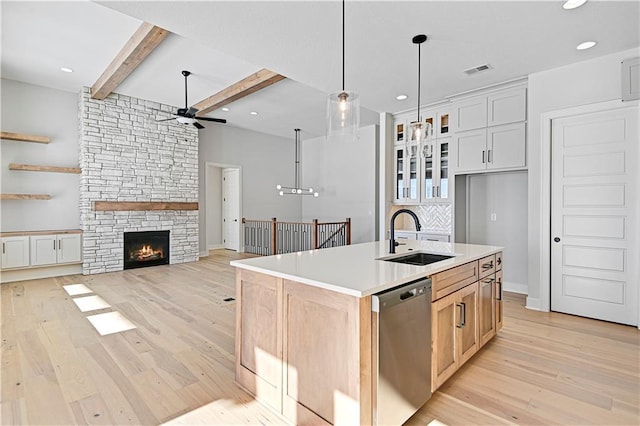 kitchen featuring white cabinetry, sink, beamed ceiling, stainless steel dishwasher, and an island with sink