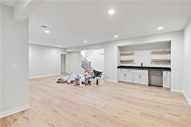 interior space featuring white cabinetry, sink, stainless steel dishwasher, and light wood-type flooring