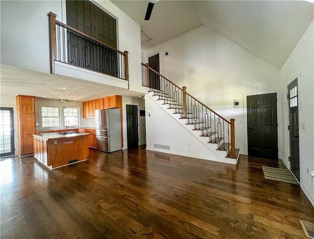 kitchen featuring stainless steel refrigerator, dark hardwood / wood-style floors, high vaulted ceiling, and a kitchen island