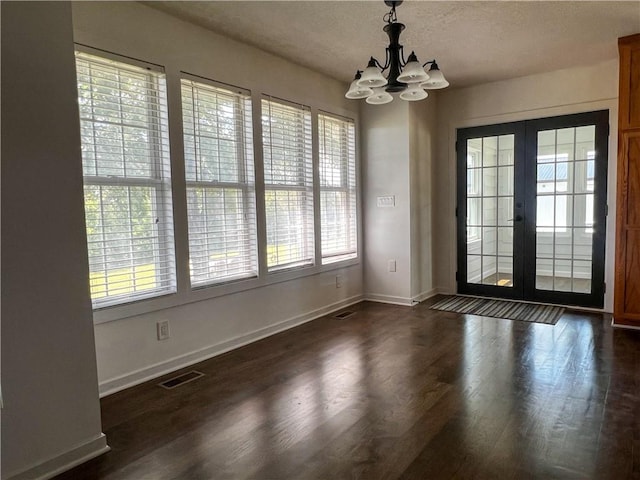 unfurnished dining area featuring dark hardwood / wood-style flooring, french doors, and a chandelier