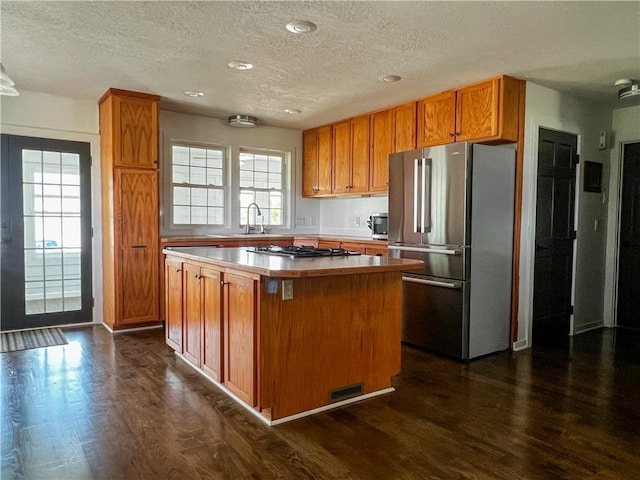 kitchen with dark hardwood / wood-style floors, stainless steel appliances, a center island, and a textured ceiling