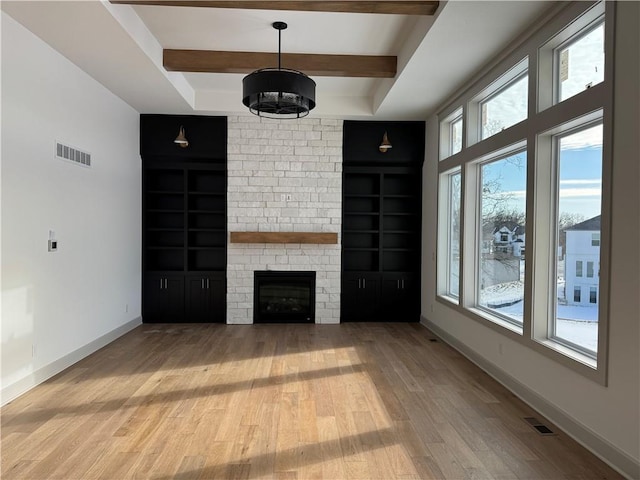 unfurnished living room featuring built in shelves, visible vents, wood finished floors, beamed ceiling, and baseboards