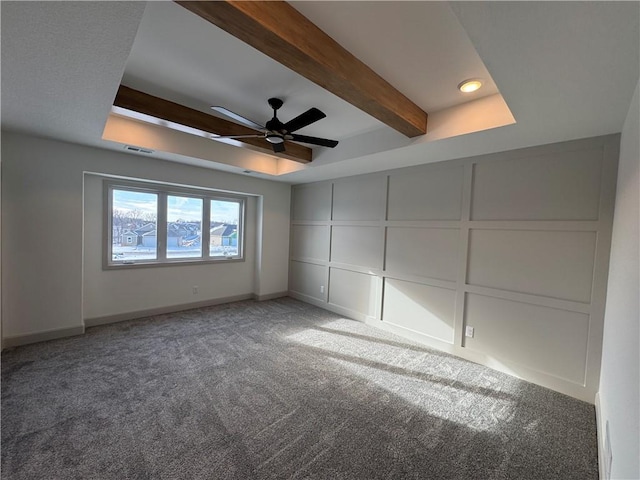 interior space with beam ceiling, a raised ceiling, a decorative wall, and visible vents