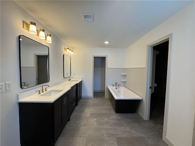 bathroom with visible vents, a sink, a bath, and double vanity