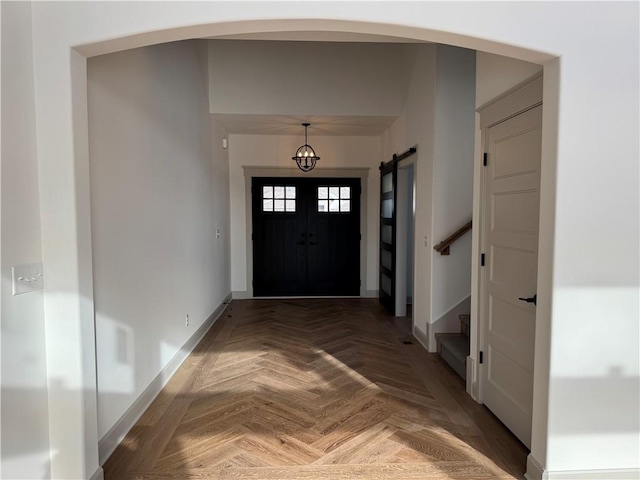 entrance foyer with arched walkways, stairway, and baseboards