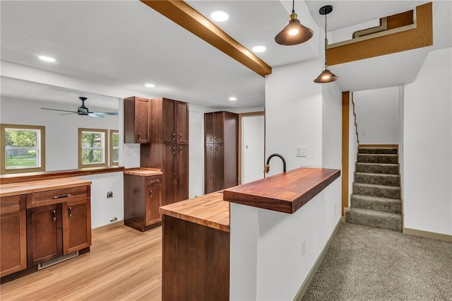 kitchen featuring ceiling fan, butcher block counters, pendant lighting, light wood-type flooring, and kitchen peninsula