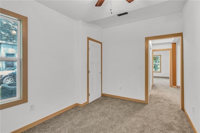 empty room featuring ceiling fan and light colored carpet