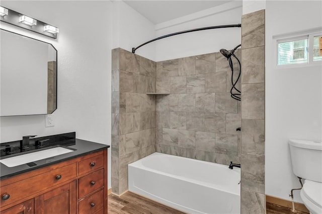 full bathroom with hardwood / wood-style flooring, toilet, vanity, and tiled shower / bath