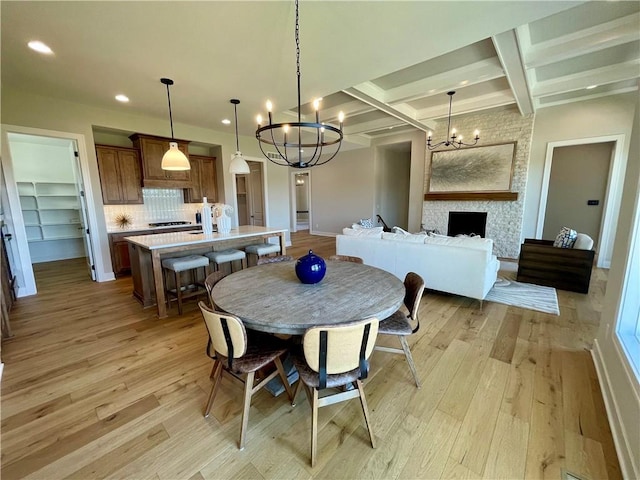 dining room with coffered ceiling, beam ceiling, a fireplace, and light hardwood / wood-style floors