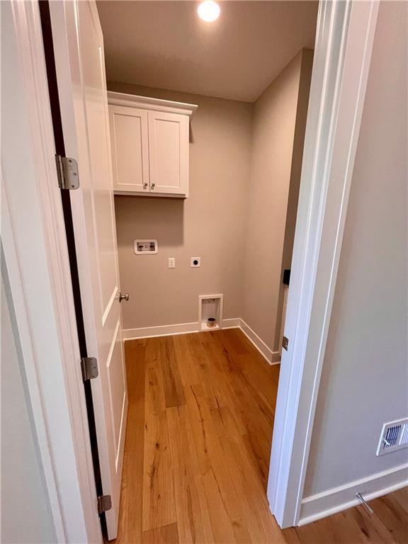 washroom with cabinets, washer hookup, hookup for an electric dryer, and light wood-type flooring