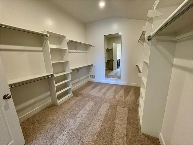 walk in closet with lofted ceiling and light colored carpet