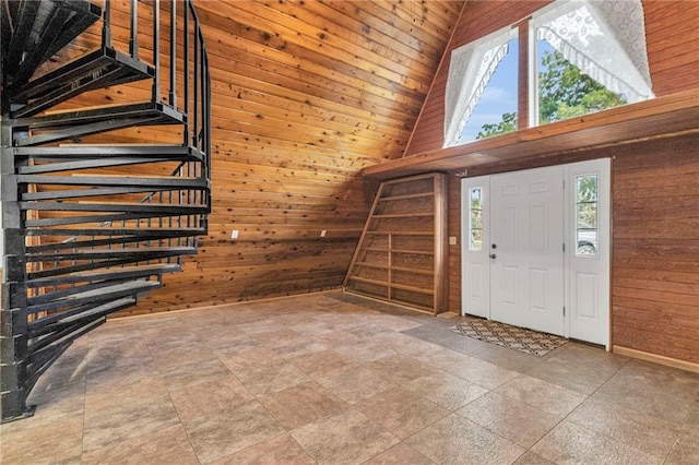 tiled entrance foyer featuring wooden walls and high vaulted ceiling