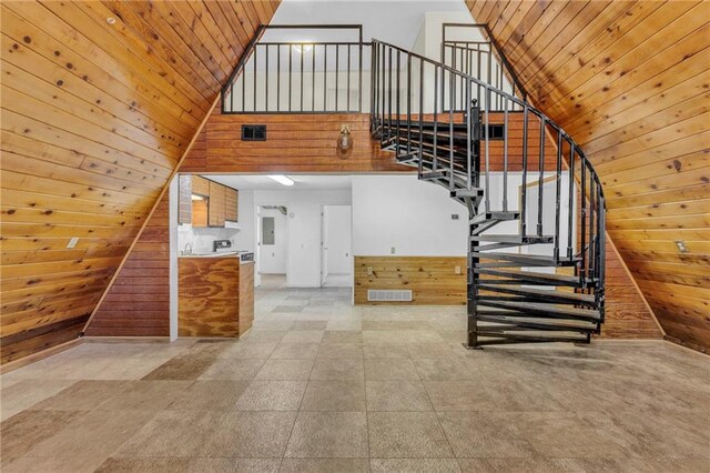 stairs with wood walls, wooden ceiling, and a towering ceiling