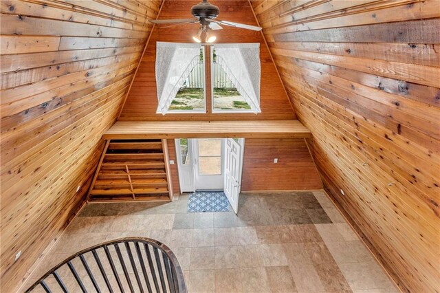 bonus room with wooden walls, ceiling fan, vaulted ceiling, and light tile patterned floors