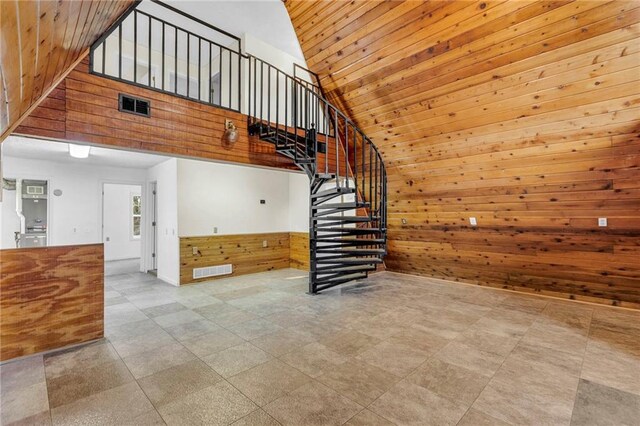 unfurnished living room featuring wood walls, light tile patterned flooring, wooden ceiling, and high vaulted ceiling