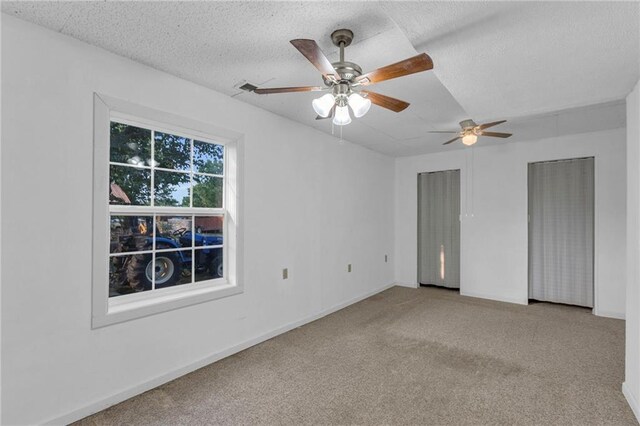 carpeted spare room featuring a textured ceiling and ceiling fan