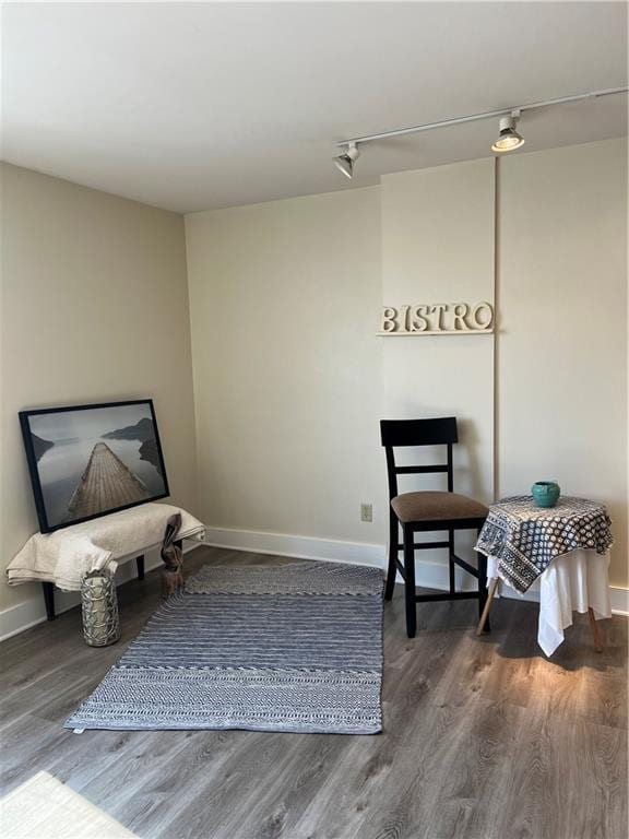 sitting room featuring rail lighting, baseboards, and wood finished floors