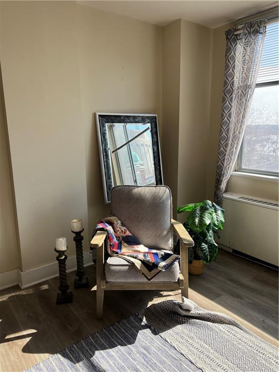 sitting room featuring radiator, wood finished floors, and baseboards