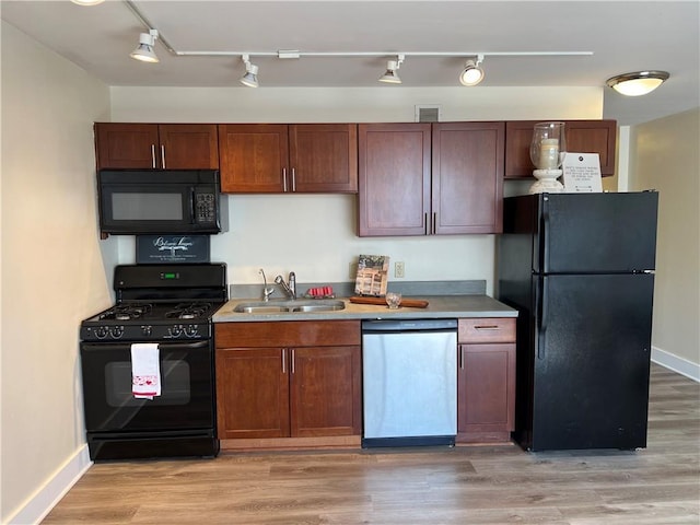 kitchen with a sink, visible vents, light countertops, light wood-type flooring, and black appliances