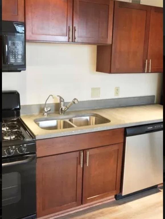 kitchen featuring light countertops, a sink, and black appliances