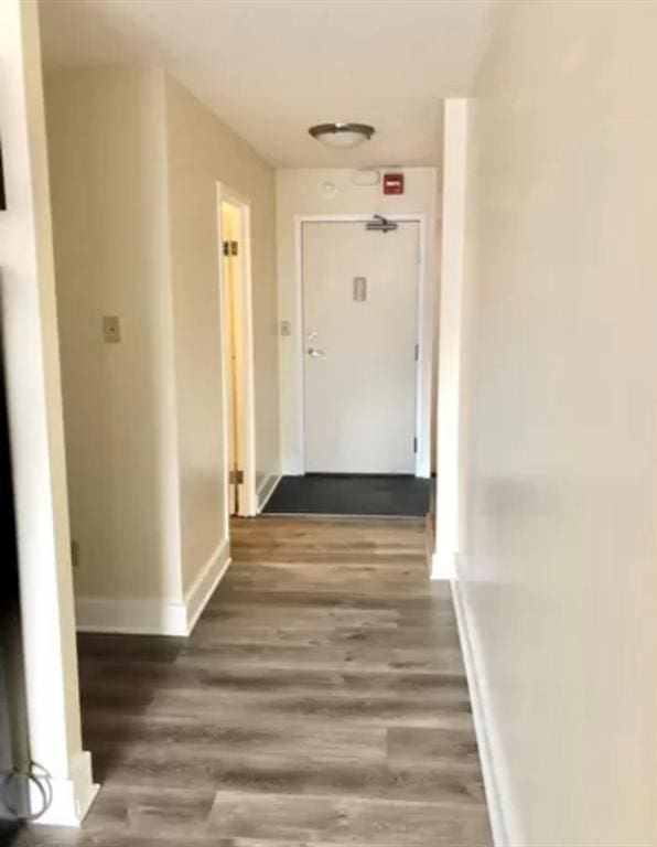 hallway featuring dark wood finished floors and baseboards