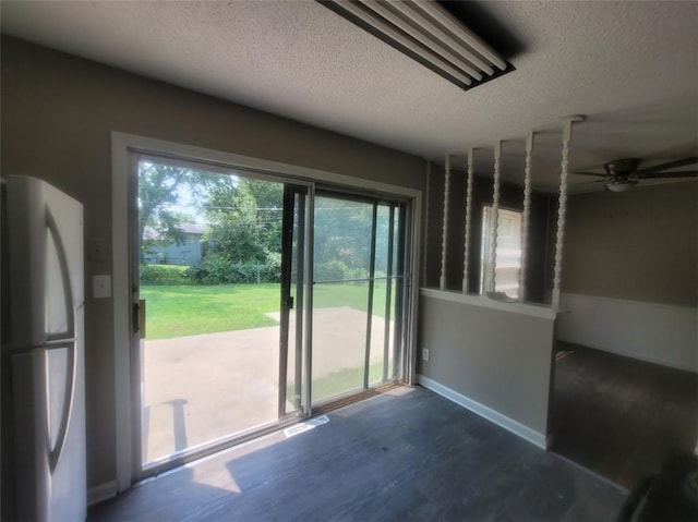 doorway featuring ceiling fan, dark hardwood / wood-style floors, and a textured ceiling