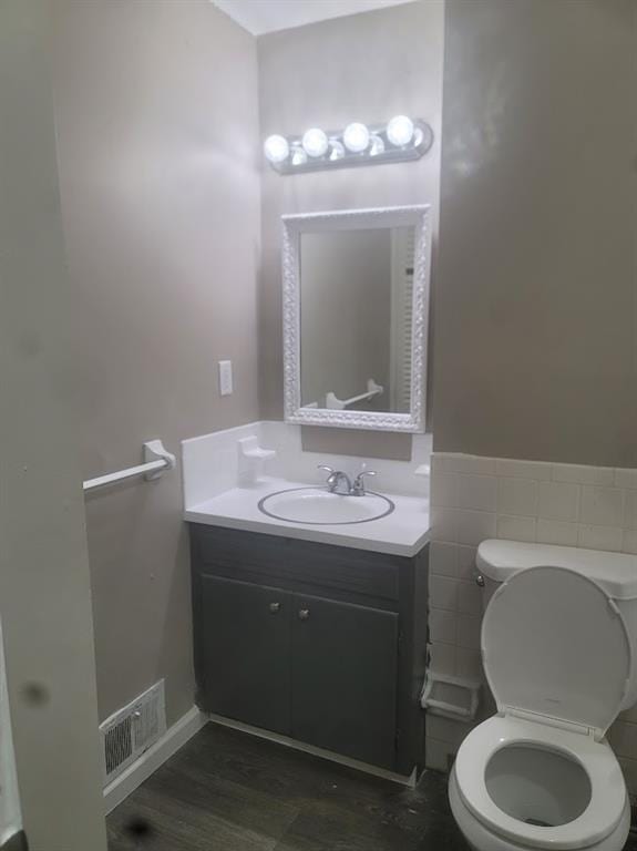 bathroom with vanity, toilet, hardwood / wood-style floors, and tile walls